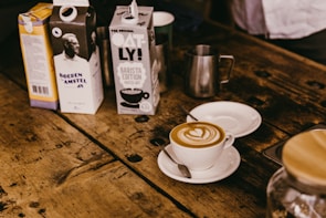 A rustic wooden table displaying a cup of lavender milk latte with soft natural lighting.