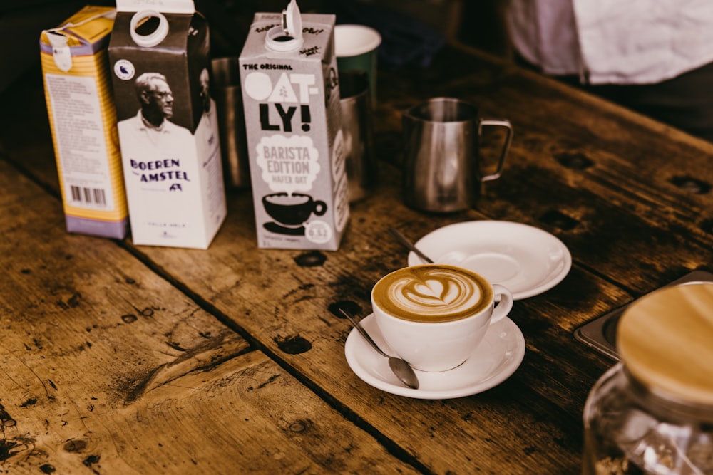 a cappuccino sits on a table next to two boxes of coffee