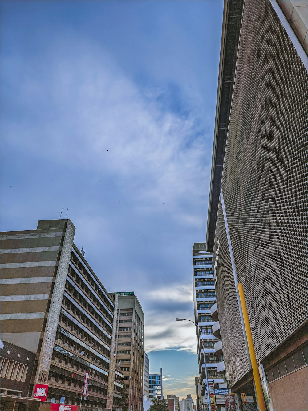 a city street lined with tall buildings under a cloudy sky