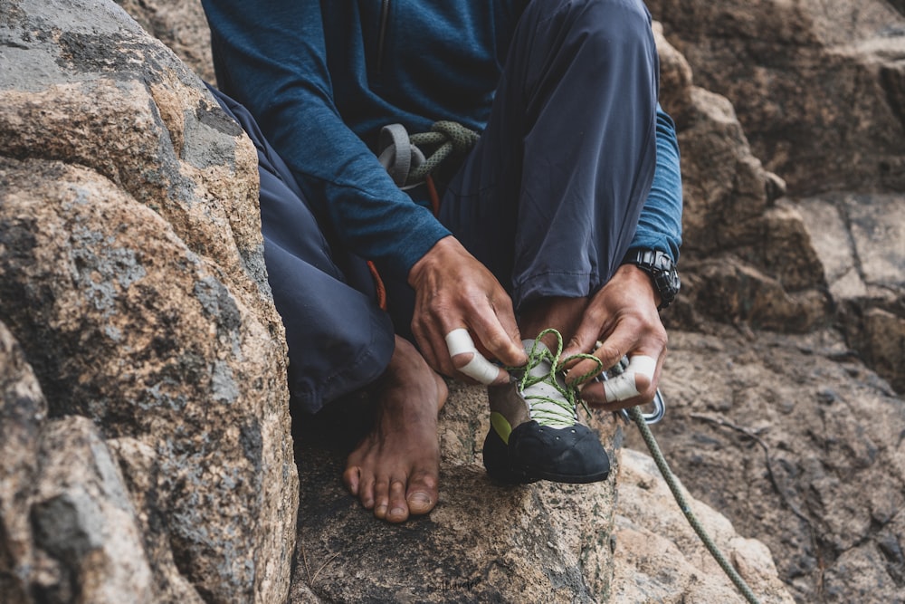 a man sitting on top of a rock next to a pair of shoes