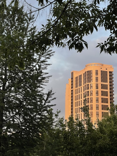 Sunlit modern apartment building with earthy-toned exterior blending into a green landscape