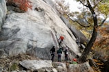 Group of climbers receiving hands-on coaching on anchor building outdoors.