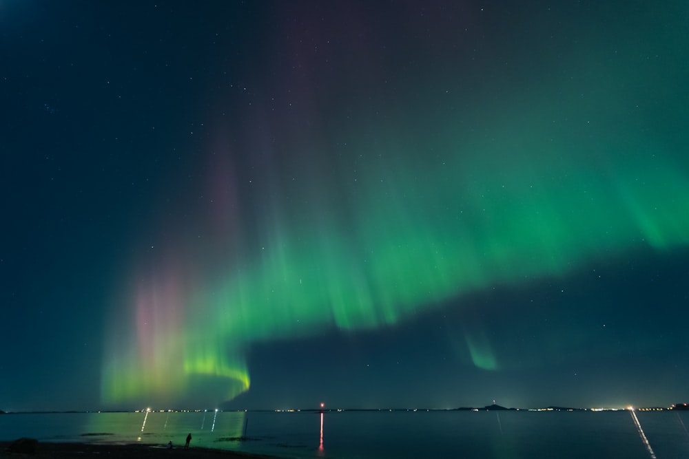 a bright green and purple aurora bore over a body of water