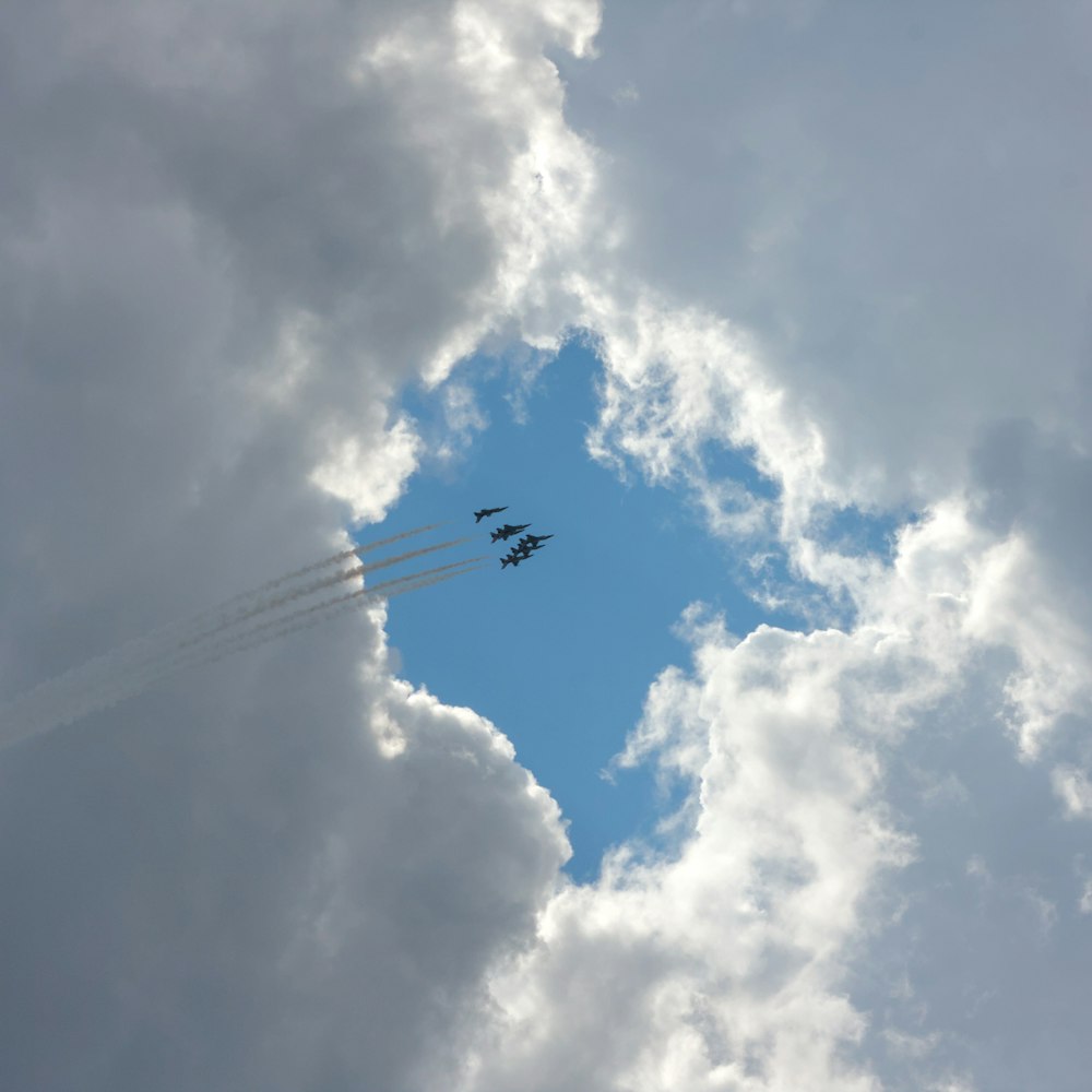 a group of jets flying through a cloudy sky