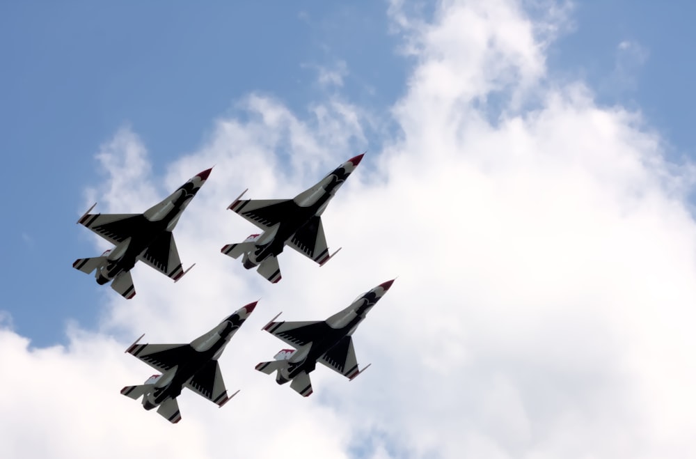 four fighter jets are flying in formation in the sky