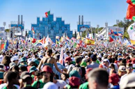 Journalists reporting live from an international summit with flags in the background.