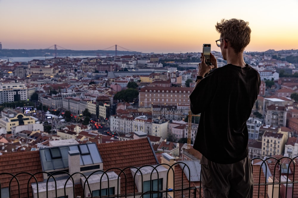 a man taking a picture of a city with a cell phone
