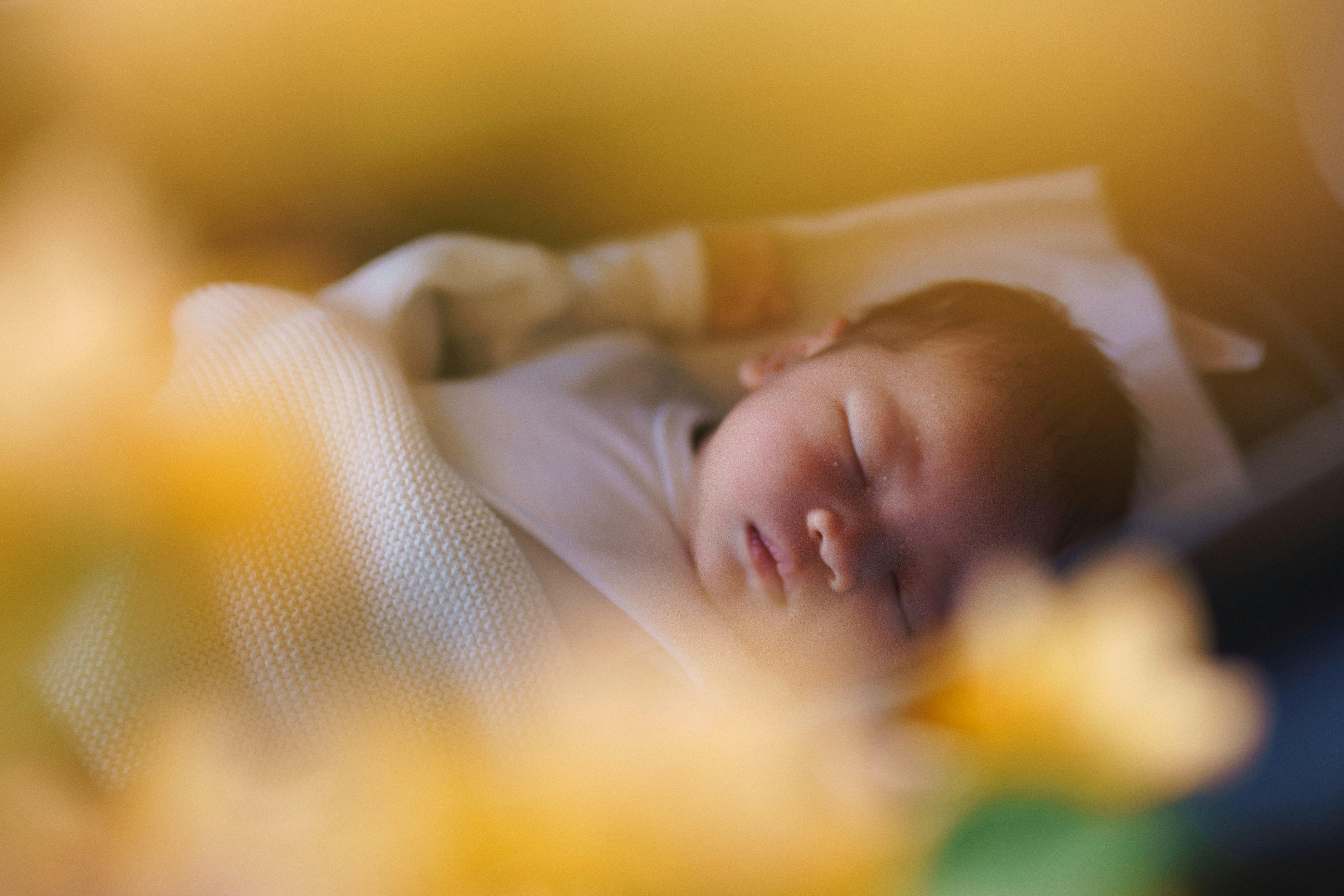 Newborn sleeping peacefully in a cozy crib with soft light