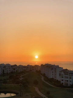 A serene sunset view over Vela Bay's sea-facing condominium towers with the Bayshore MRT station in the foreground.
