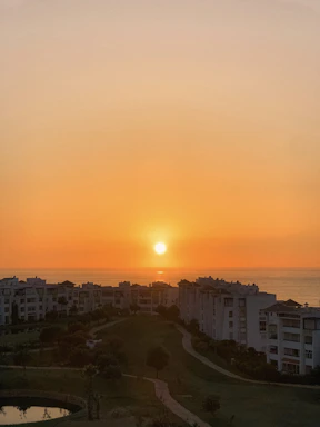 A serene sunset view over Vela Bay's sea-facing condominium towers with the Bayshore MRT station in the foreground.