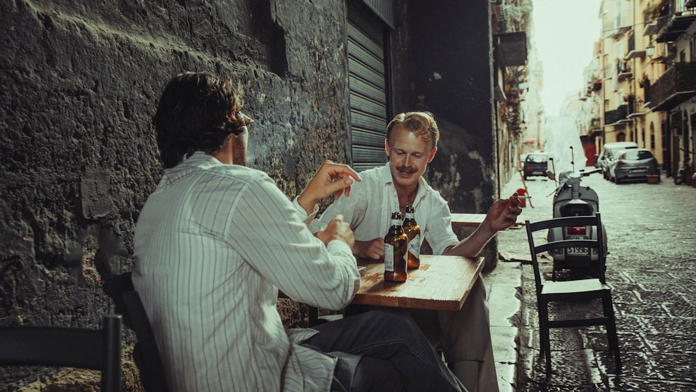 a couple of men sitting at a wooden table