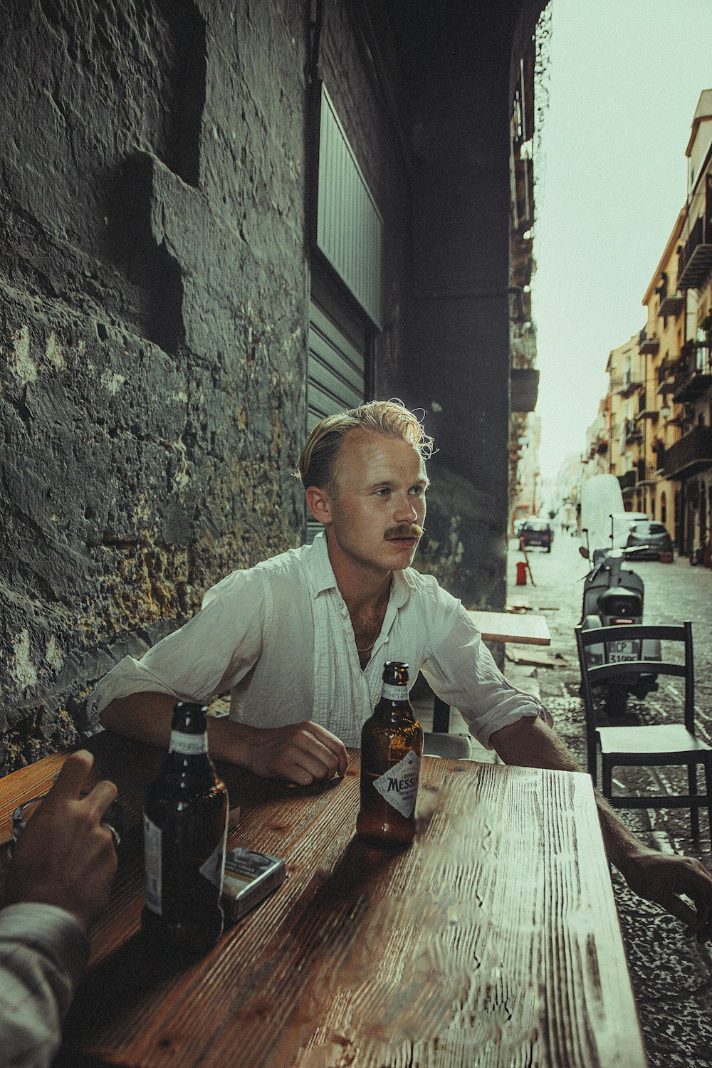 a man sitting at a table with two bottles of beer