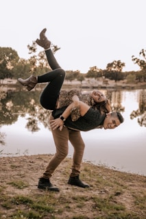 a man and a woman doing a handstand in front of a lake
