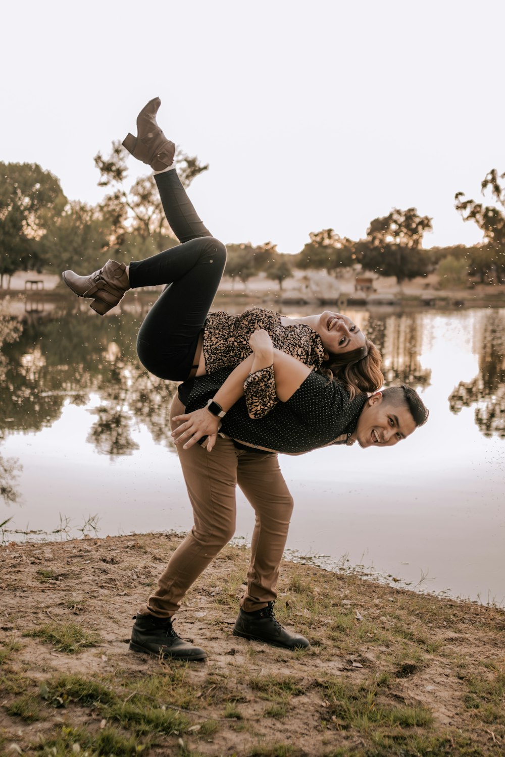 a man and a woman doing a handstand in front of a lake