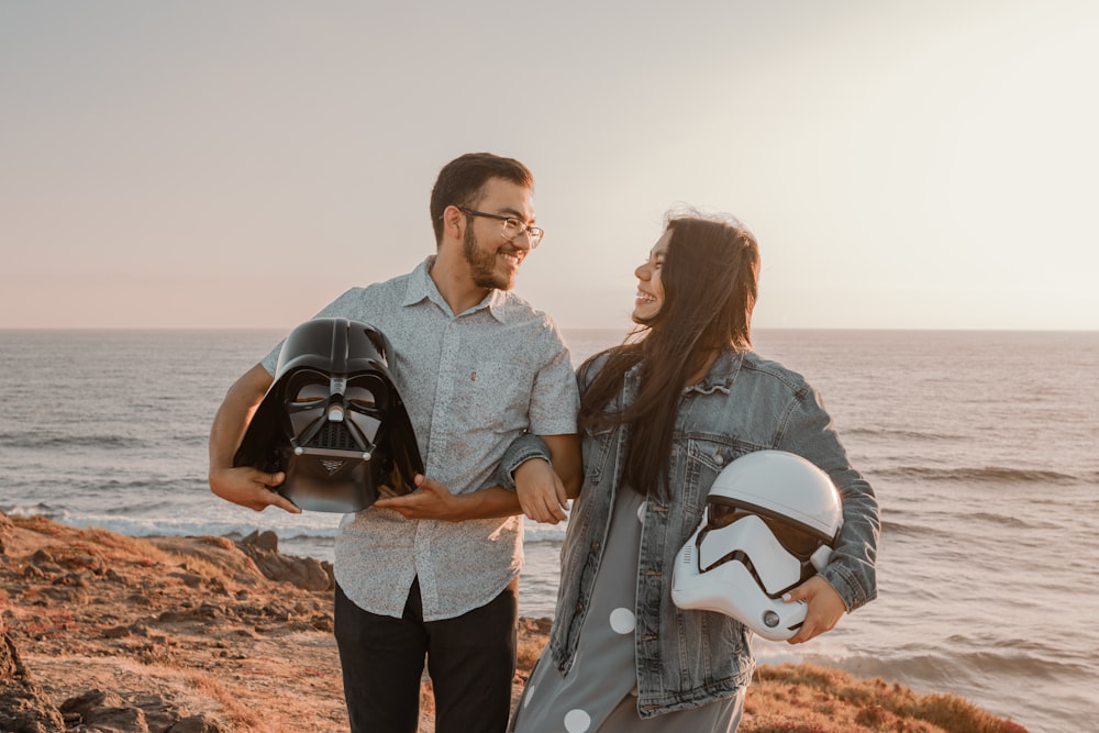 a man and a woman standing next to each other near the ocean