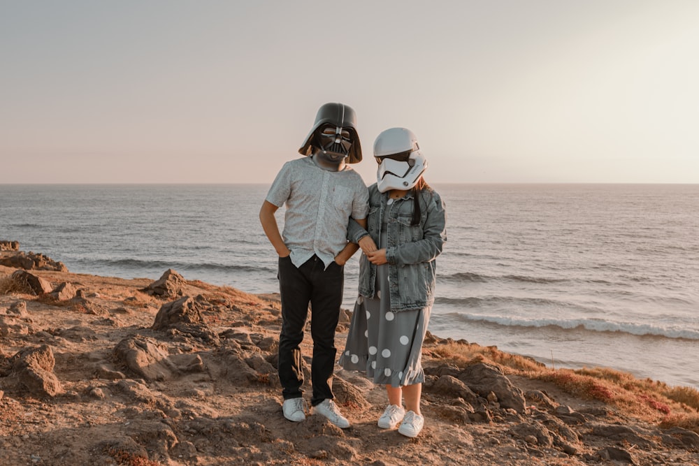 a couple of people standing on top of a sandy beach