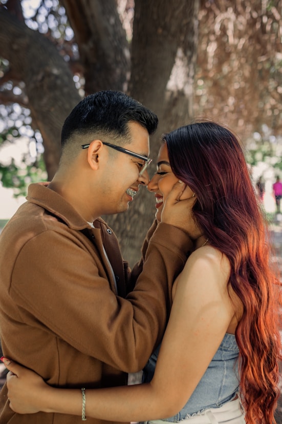 a man and a woman standing next to each other under a tree