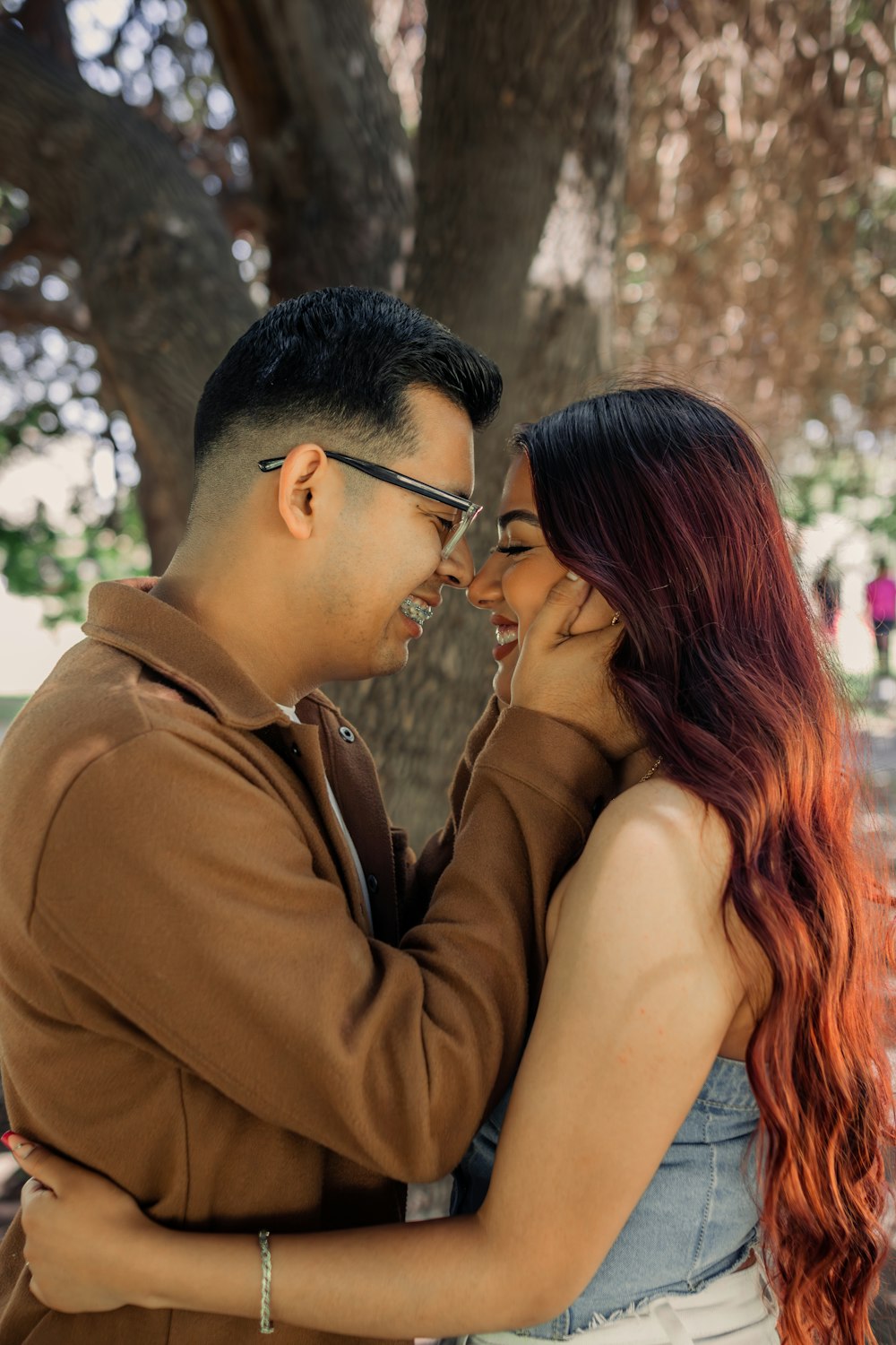 a man and a woman standing next to each other under a tree