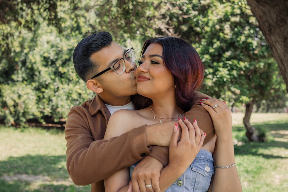 a man and a woman embracing each other in a park