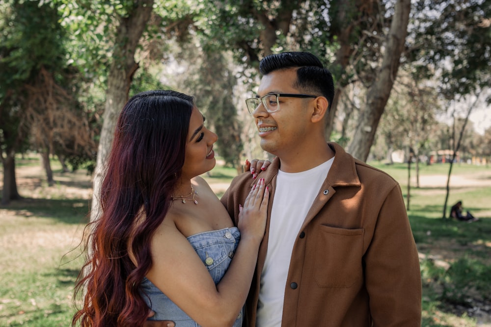 a man and woman standing next to each other in a park