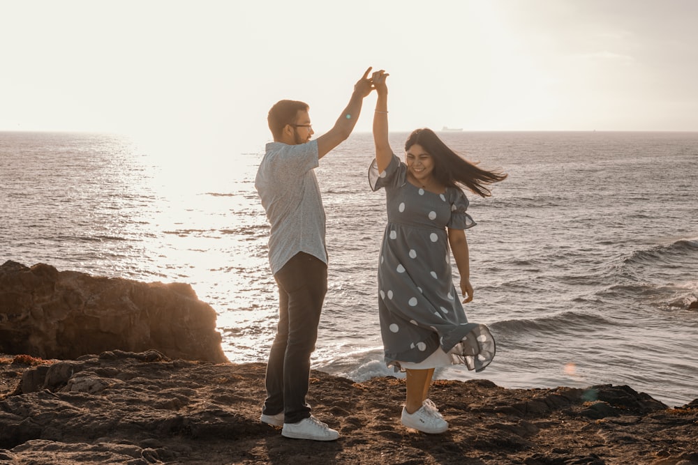 a man and a woman dancing on a rocky beach