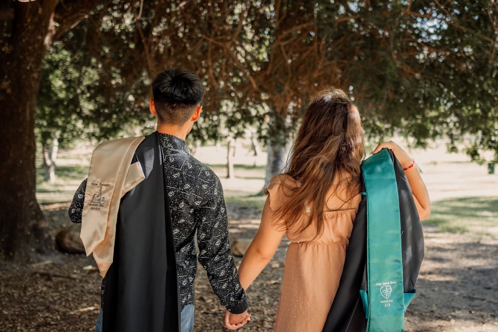 a man and a woman holding hands under a tree