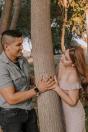 a man and a woman standing next to a tree