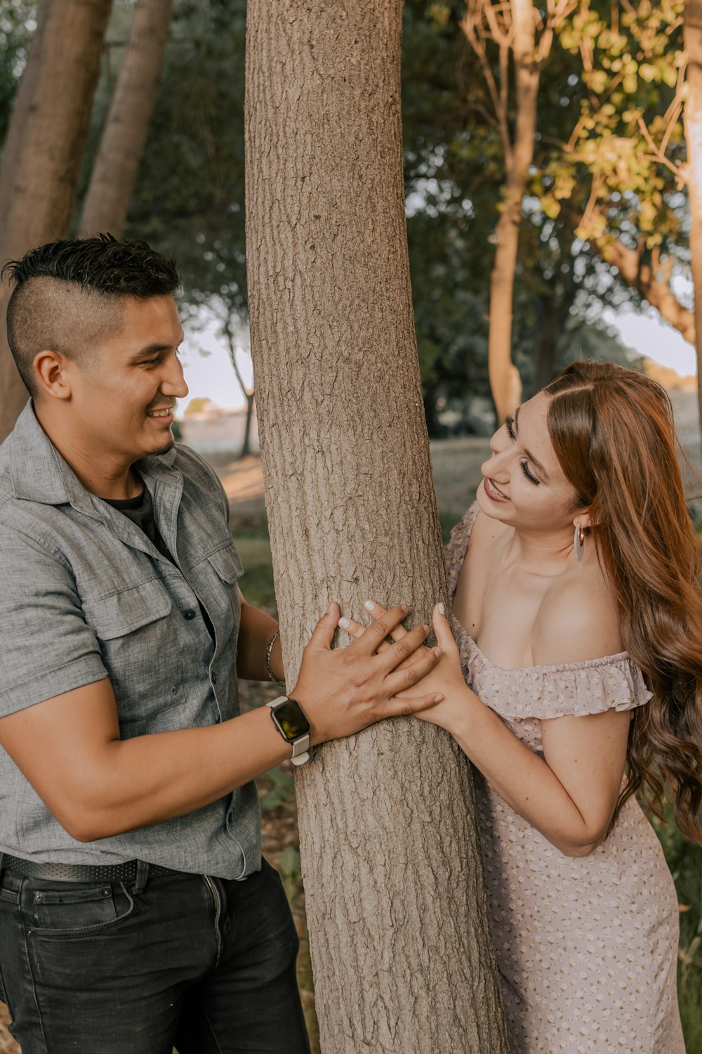 a man and a woman standing next to a tree