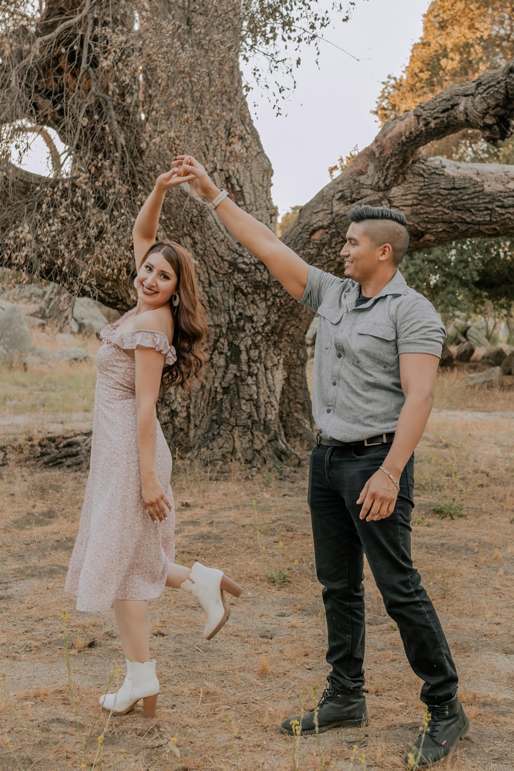 um homem e uma mulher dançando em frente a uma árvore