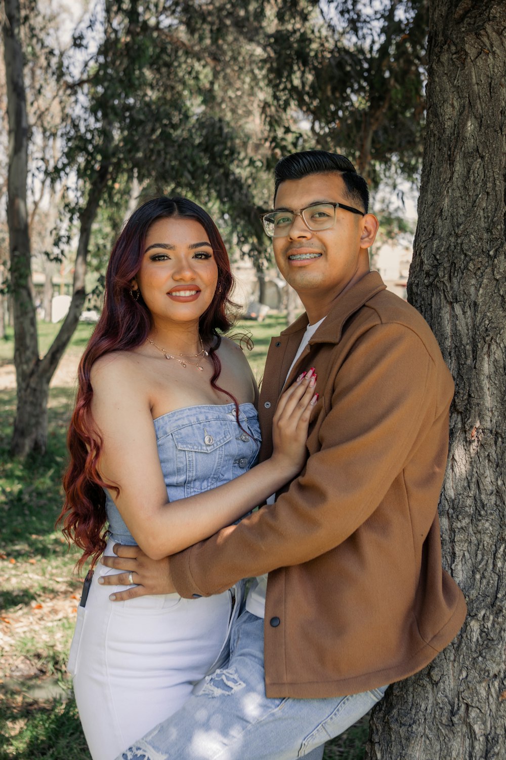 a man and a woman standing next to a tree