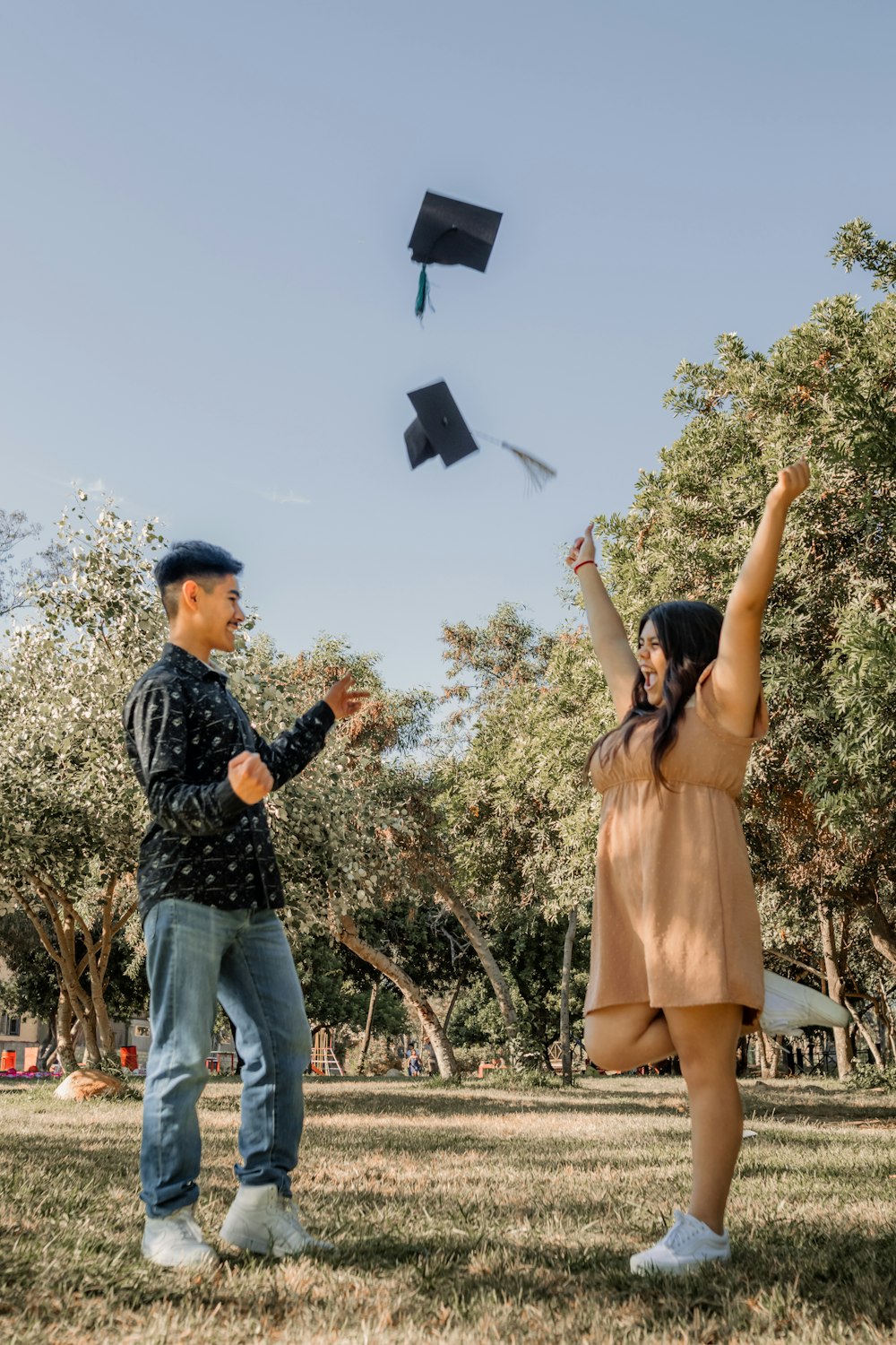 a man and a woman throwing graduation caps in the air