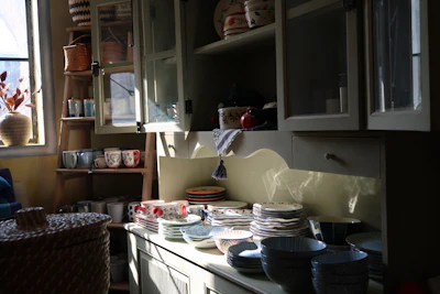 A cozy kitchen scene featuring colorful ceramic bowls stacked beside a window with soft morning light.