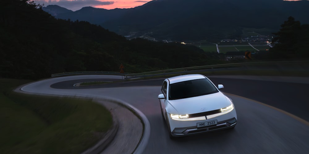 a white car driving down a winding road