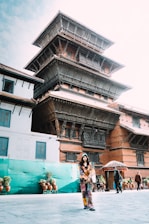 A welcoming local guide smiling warmly in front of a Buddhist temple.
