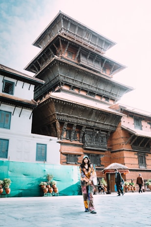 A welcoming local guide smiling warmly in front of a Buddhist temple.