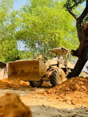 Mike Jensen operating a bobcat skidsteer amidst tall trees and freshly cleared land.
