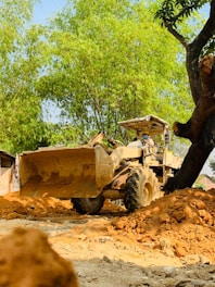 A bulldozer pushing aside trees and brush under a bright sky.