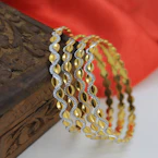 Close-up of a deep maroon velvet box holding an antique gold temple necklace set against an ivory silk backdrop.