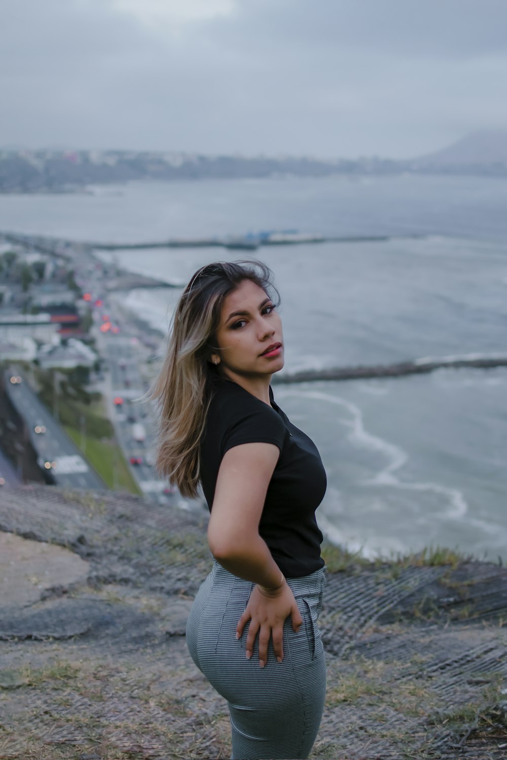 a woman standing on top of a hill next to the ocean