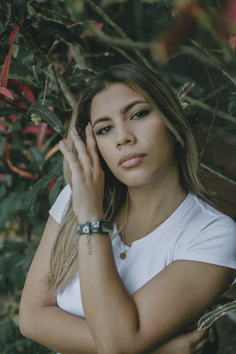 a beautiful young woman leaning against a tree