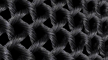 Interwoven strands of dark, metallic wires form a textured, lattice-like pattern. The intricate braiding creates a sense of depth and complexity, with highlights emphasizing the reflective surface of the materials.