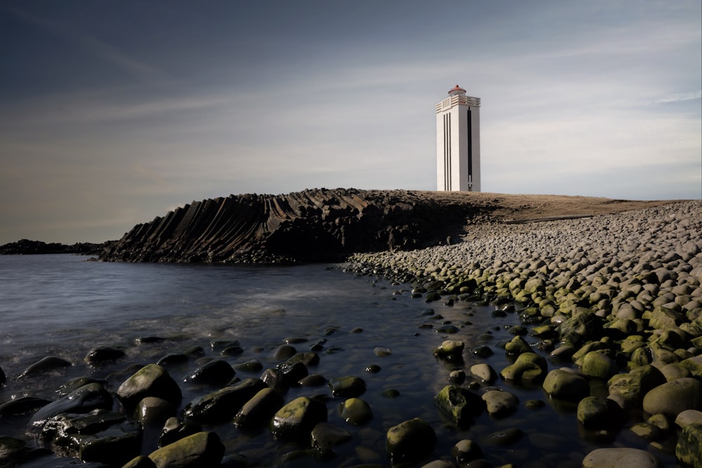 a lighthouse on a rocky shore with a body of water
