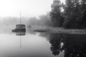 A tranquil houseboat floating on a misty mountain lake at dawn.