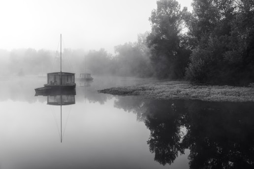 A tranquil houseboat floating on a misty mountain lake at dawn.