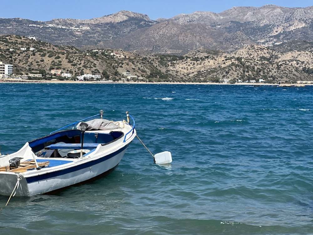 a blue and white boat floating on top of a body of water
