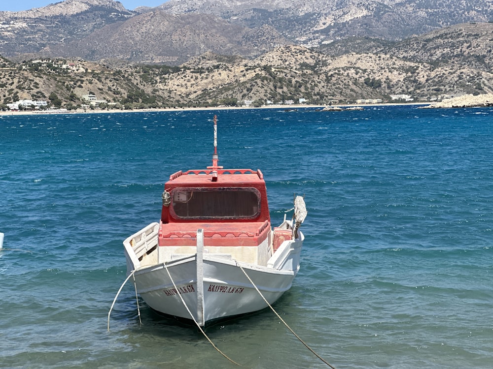 a red and white boat floating on top of a body of water