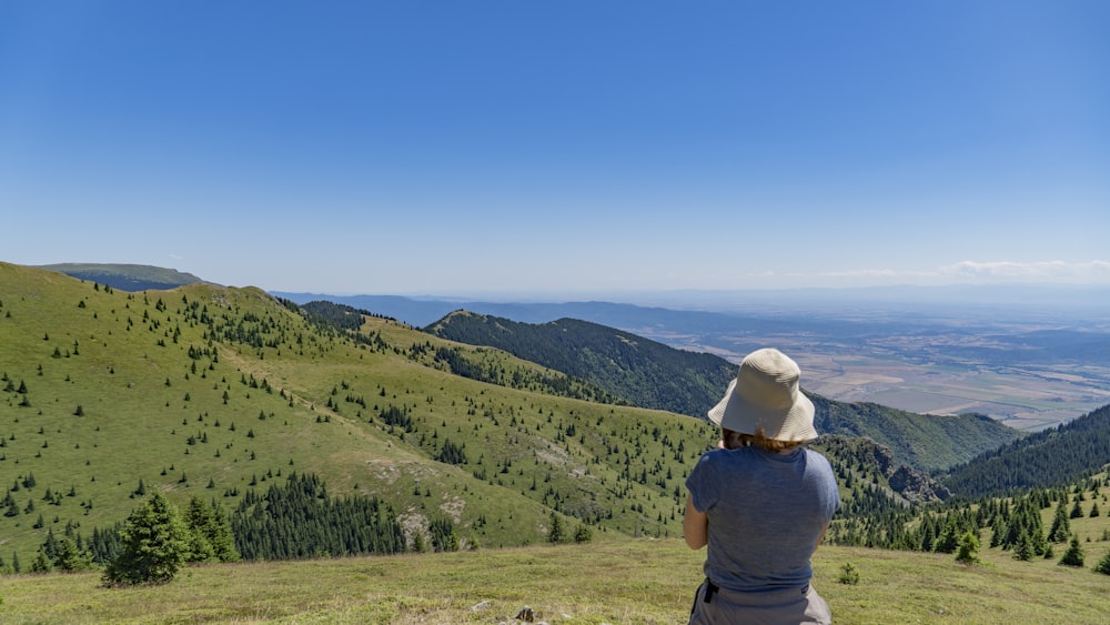 a woman sitting on top of a lush green hillside