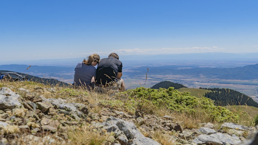 un paio di persone sedute sulla cima di una collina