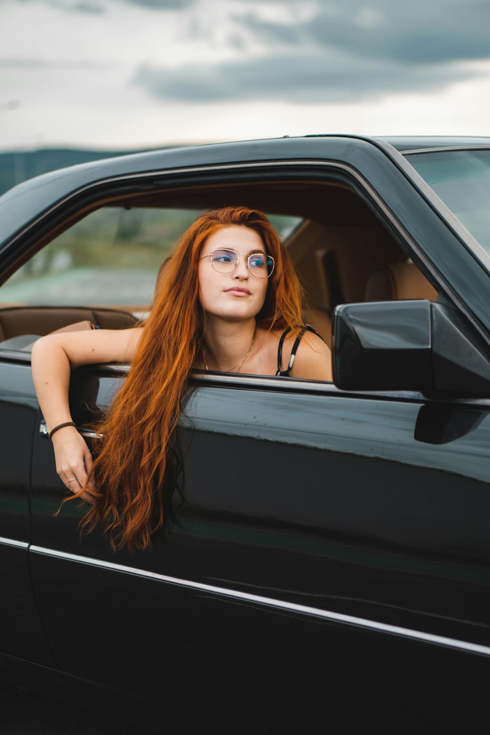 a woman with long red hair sitting in a car