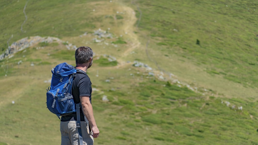 Un hombre con una mochila azul de pie en la cima de una colina